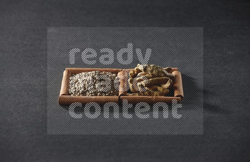 2 squares of cinnamon sticks full of white pepper and turmeric fingers on black flooring