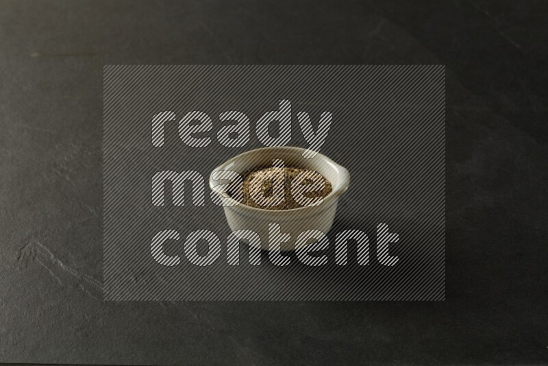 white ceramic round sauce bowl filled with herbs on grey textured countertop