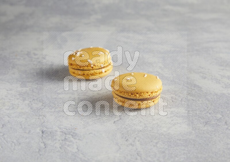 45º Shot of two Yellow Piña Colada macarons  on white  marble background