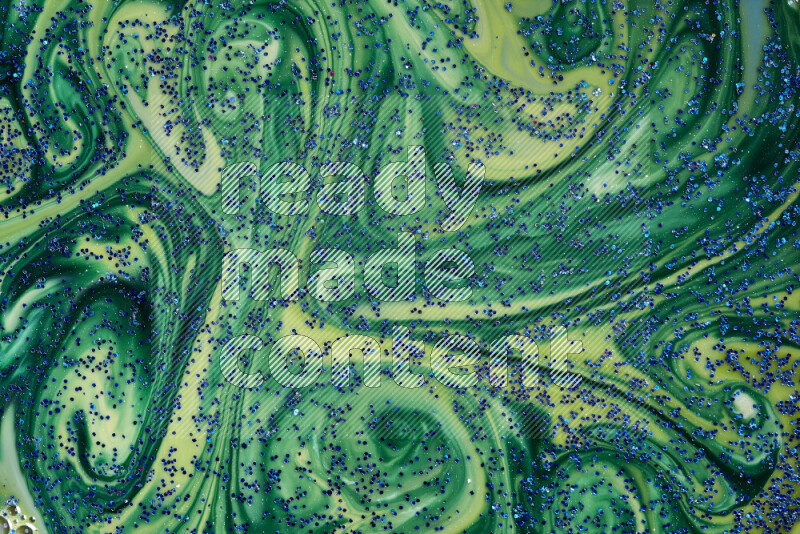 A close-up of sparkling blue glitter scattered on swirling blue and green background