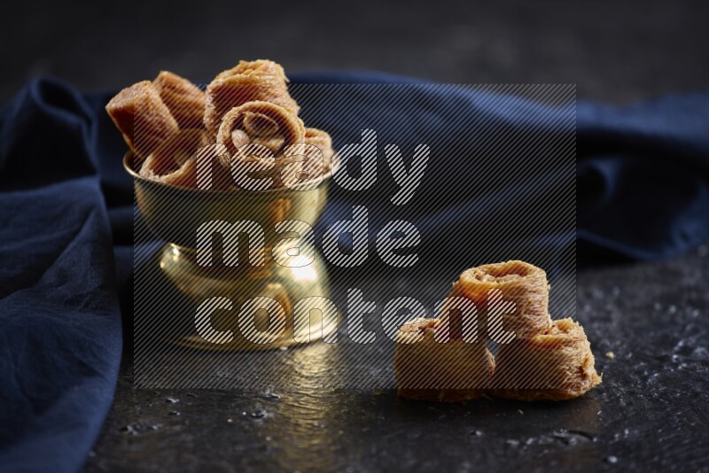 أساور كنافة في وعاء معدني علي خلفية سوداء