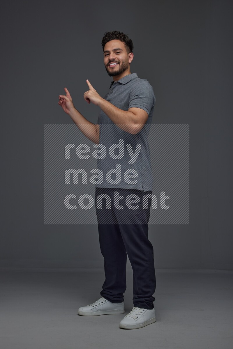 A man wearing casual standing and making multi hand gestures eye level on a gray background
