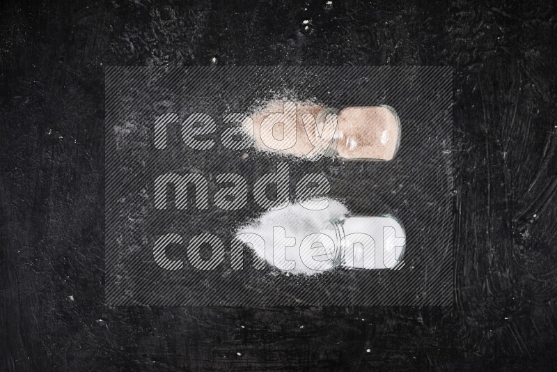 2 glass jars one is filled with fine himalayan salt and the other with table salt on black background