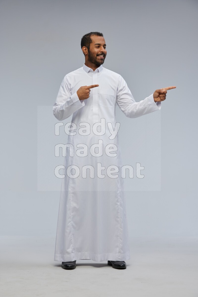 Saudi man Wearing Thob standing interacting with the camera on Gray background