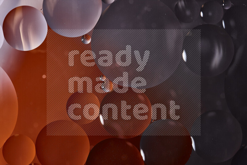 Close-ups of abstract oil bubbles on water surface in shades of black and orange
