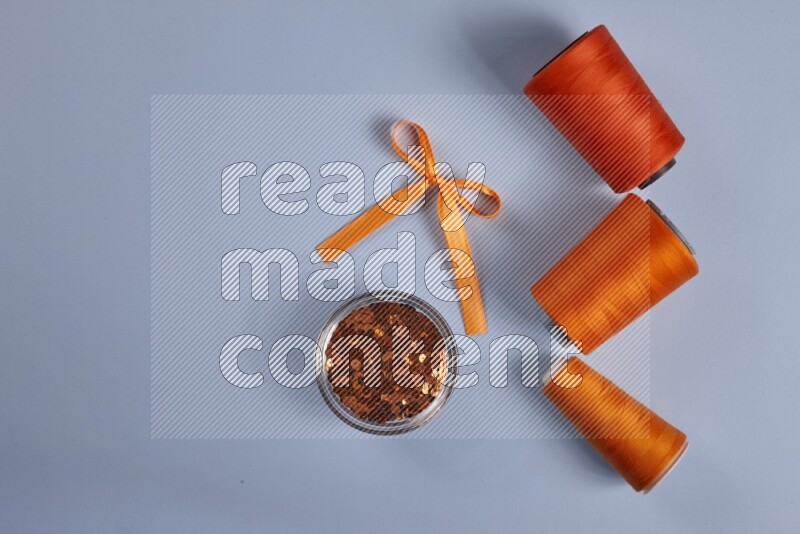 An orange collection of sewing and tailoring tools arranged on a blue background