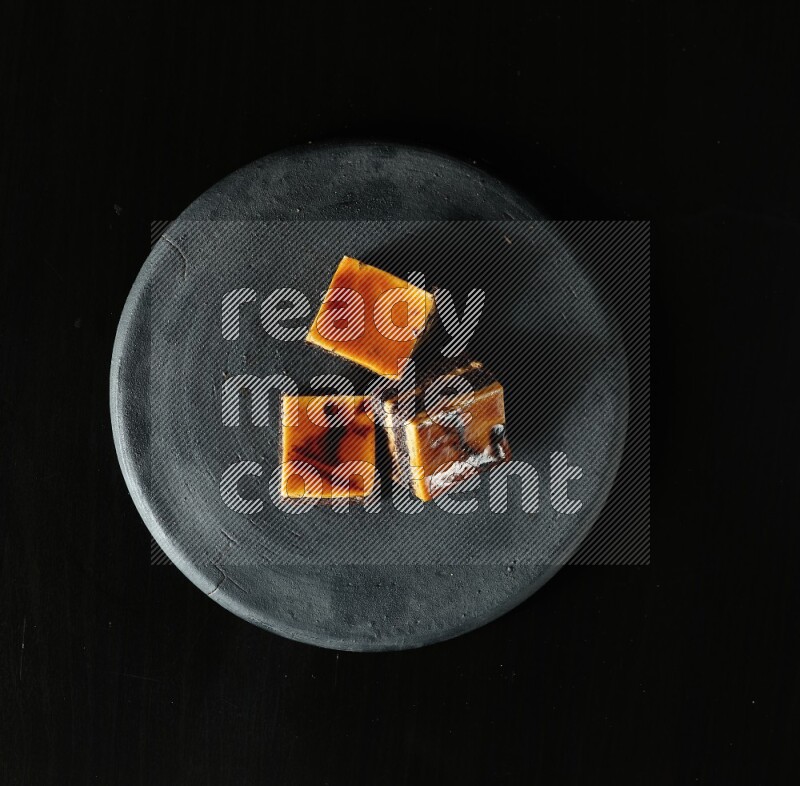 Assorted desserts in a black pottery plate on black background
