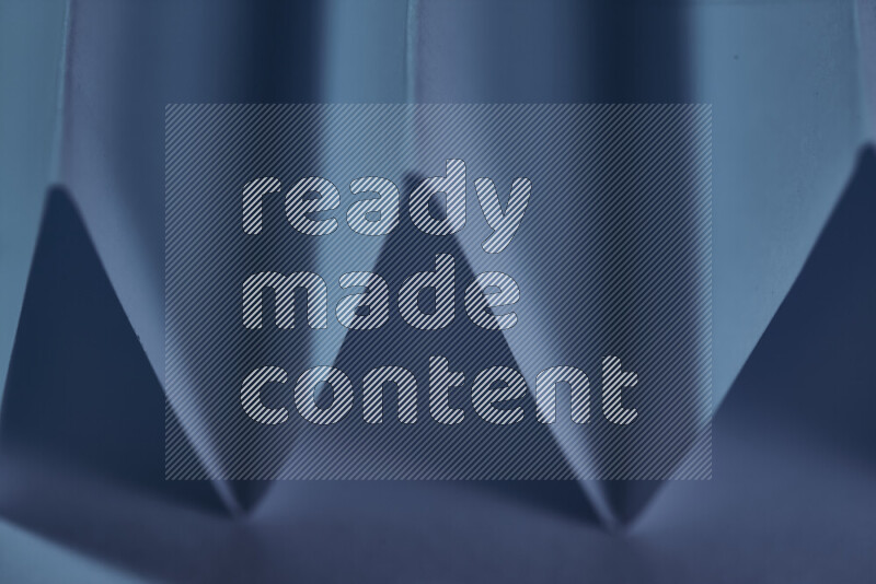 A close-up abstract image showing sharp geometric paper folds in blue gradients