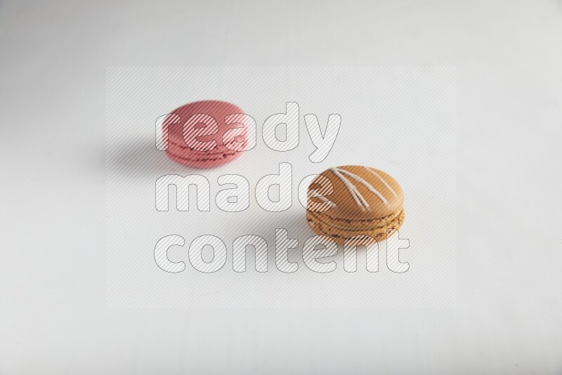 45º Shot of of two assorted Brown Irish Cream, and Pink Raspberry macarons on white background
