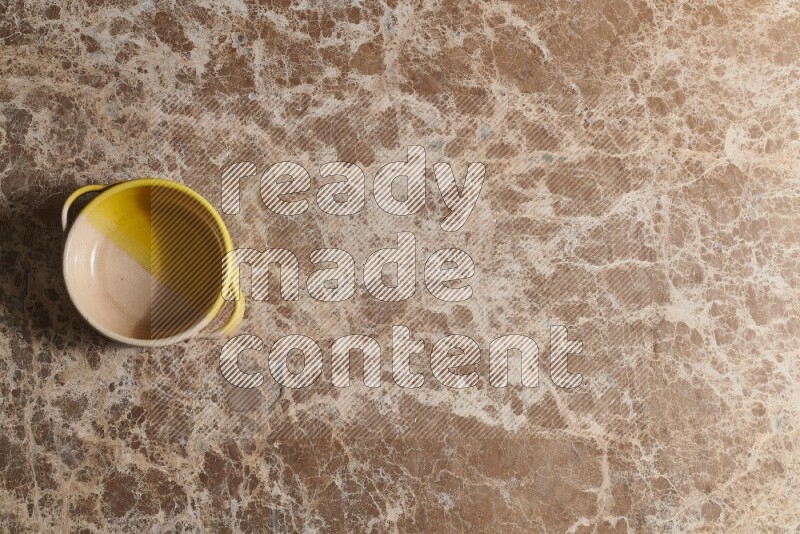 A multicolored pottery bowl on beige marble background