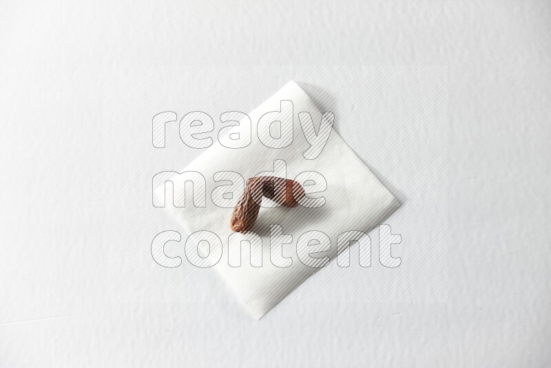 Two dried dates on a piece of paper on a white background in different angles