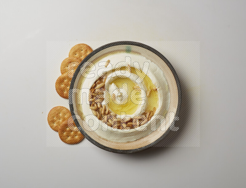 Lebnah garnished with pine nuts in a pottery plate on a white background