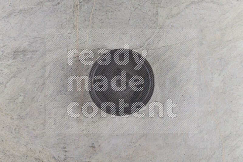 A black pottery oven bowl on grey marble background