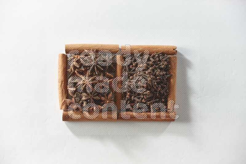 مربعان من أعواد القرفة ممتلئان بالقرنفل واليانسون النجمي علي خلفية بيضاء