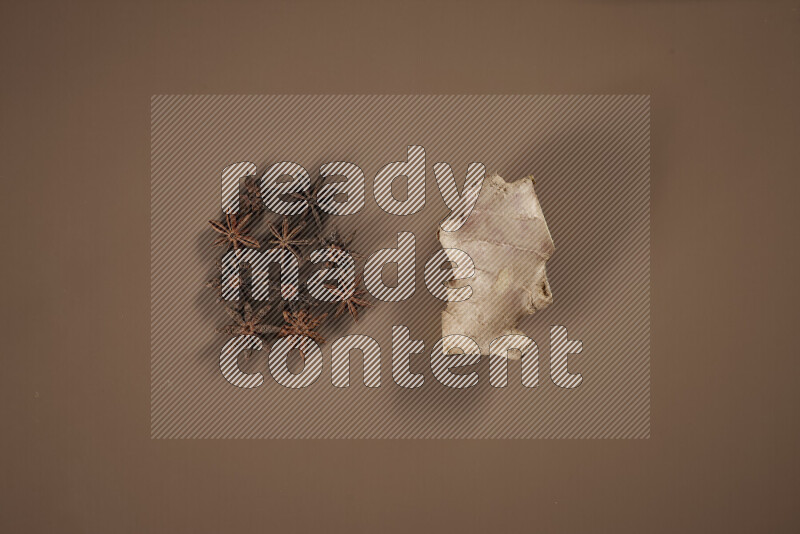 بهارات كاملة متنوعة تتضمن زنجبيل طازج ومجفف، أعواد قرفة، هيل، أصابع كركم، قرنفل، يانسون نجمي على خلفية بيج