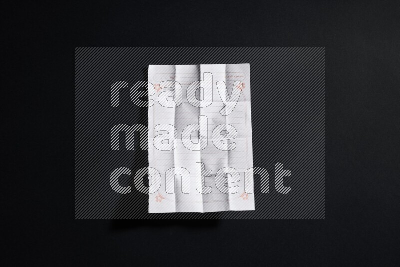 Folded notebook sheet on black background