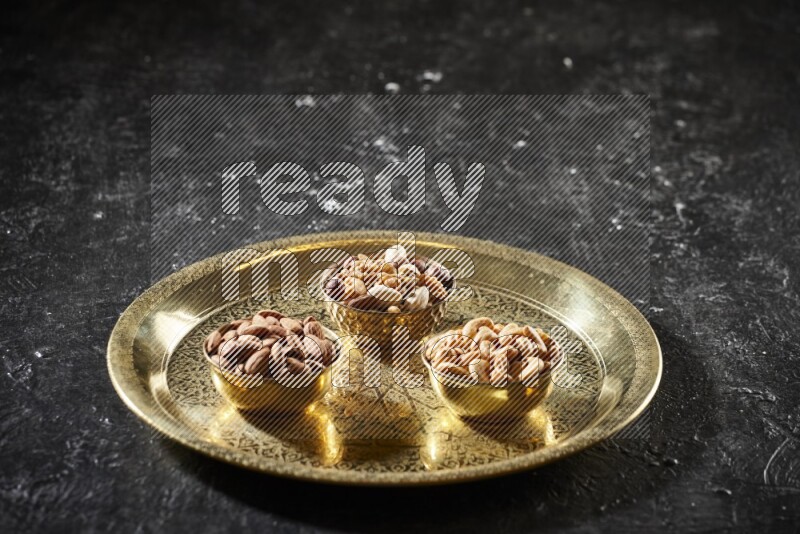 Nuts in metal bowls on a tray in a dark setup