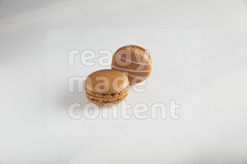45º Shot of of two assorted Brown Irish Cream, and Brown Maple Taffy macarons  on white background