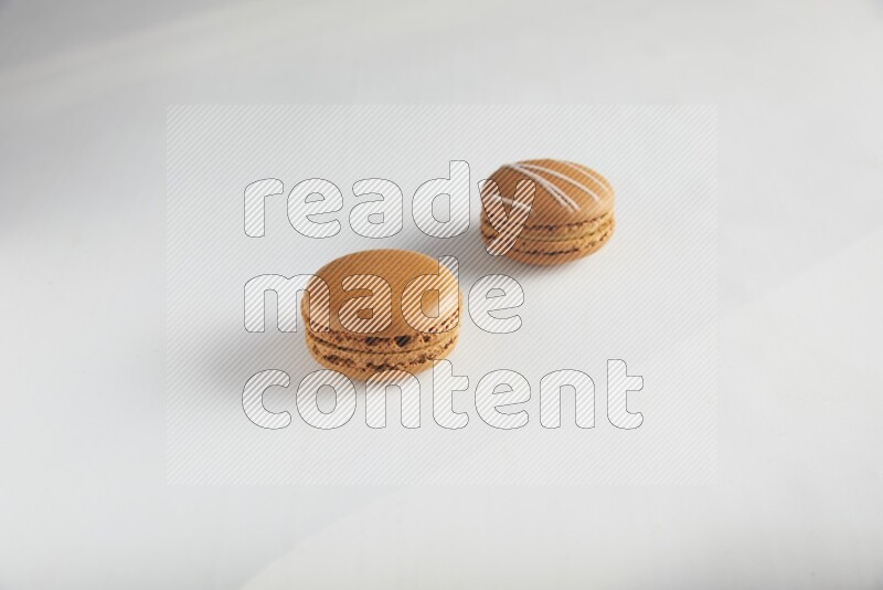 45º Shot of of two assorted Brown Irish Cream, and Brown Maple Taffy macarons  on white background