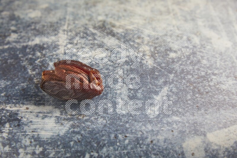 pecan stuffed madjoul date on a rustic blue background