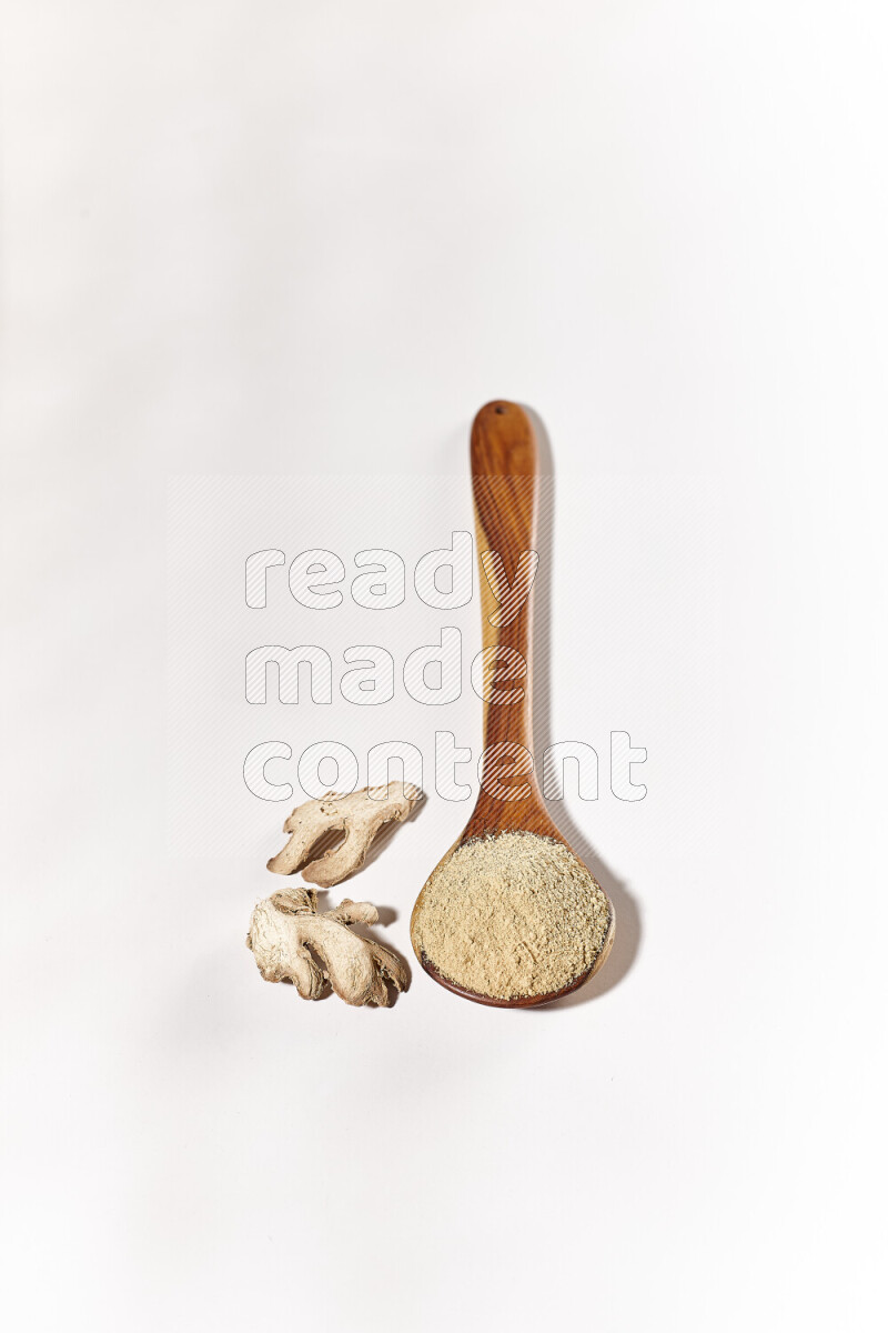 A wooden ladle full of ground ginger powder on white background