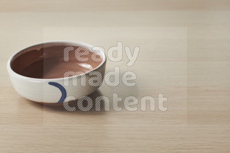 A multicolored pottery bowl on light wooden background