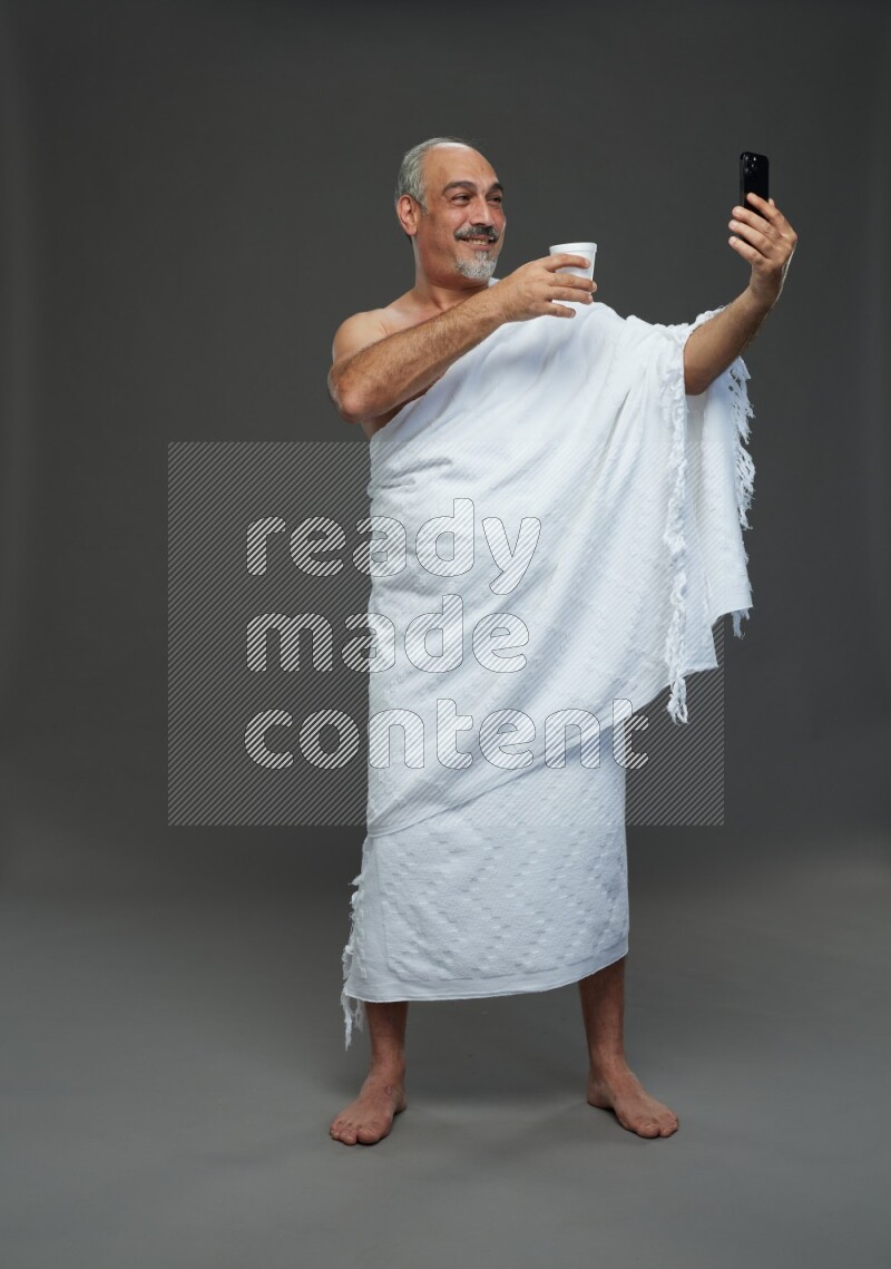 A man wearing Ehram Standing taking selfie on gray background