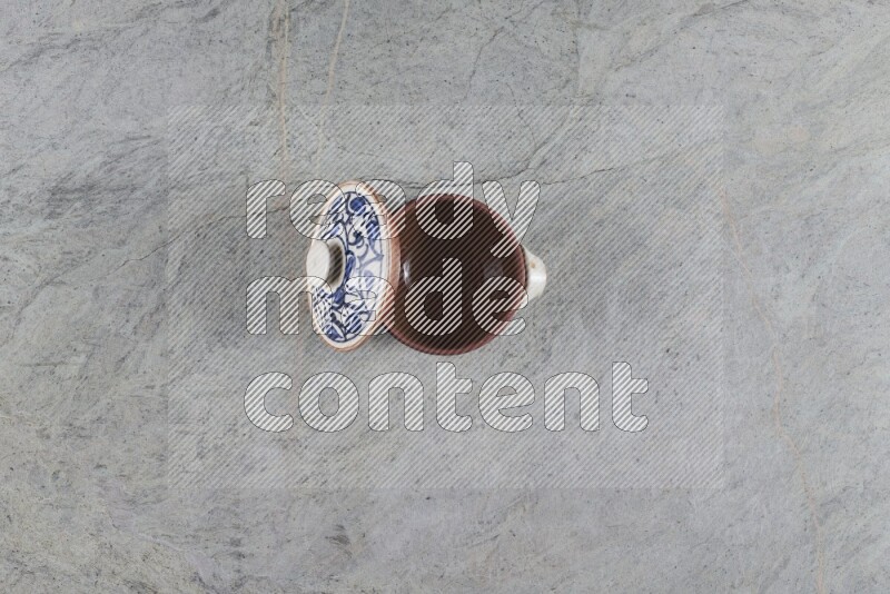 A multicolored pottery pot with its lid on grey marble background
