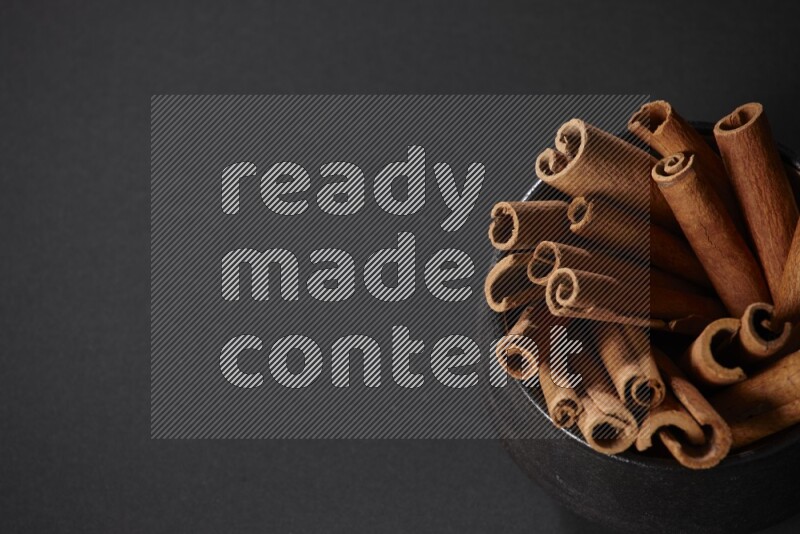 Cinnamon sticks in a black bowl on a black background in different angles