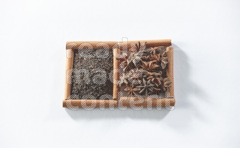 مربعان من أعواد القرفة ممتلئان بالشاي الأسود واليانسون النجمي علي خلفية بيضاء