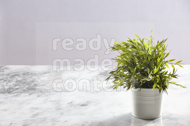 Green artificial plant in white pot on light grey marble background