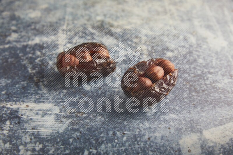 two hazelnuts stuffed madjoul dates on a rustic blue background
