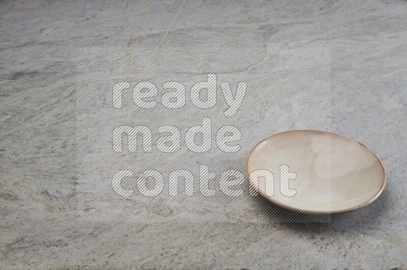 A beige pottery plate on grey marble background