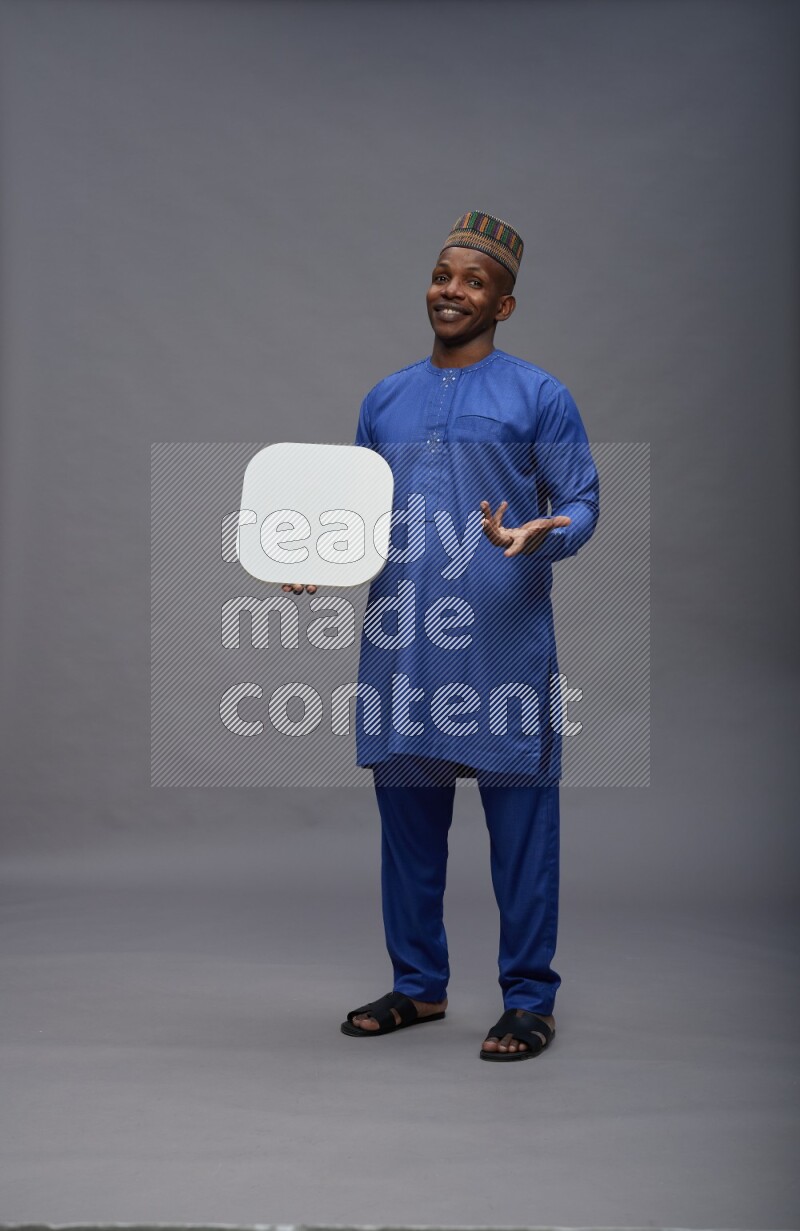 Man wearing Nigerian outfit standing holding social media sign on gray background