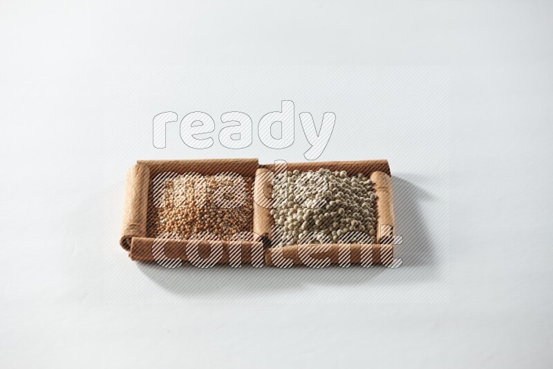 2 squares of cinnamon sticks full of mustard seeds and white pepper on white flooring