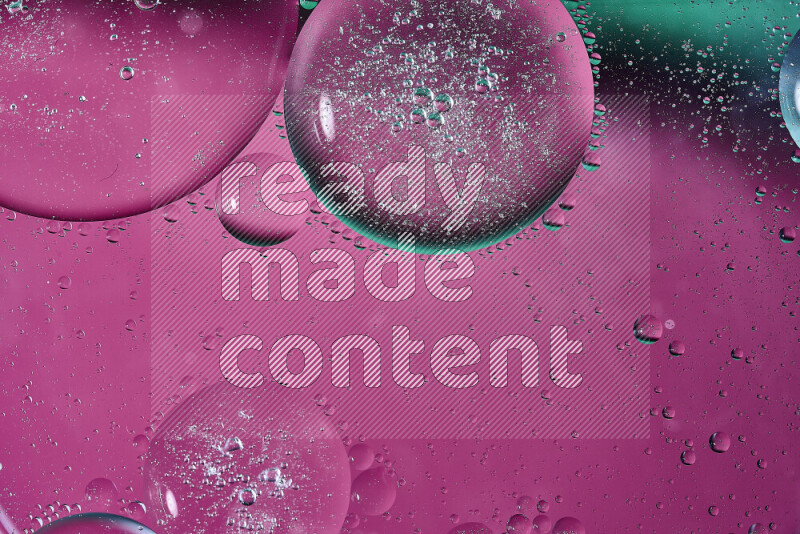 لقطات مقربة لفقاعات من الزيت على سطح الماء باللون الأخضر والوردي