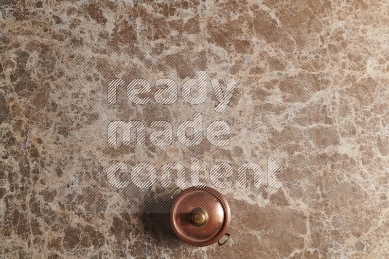 A small copper pot on beige marble background
