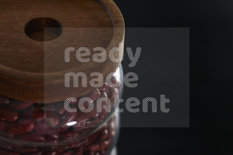 Red kidney beans in a glass jar on black background
