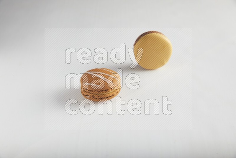 45º Shot of of two assorted Brown Irish Cream, and Yellow, and Brown Chai Latte macarons on white background