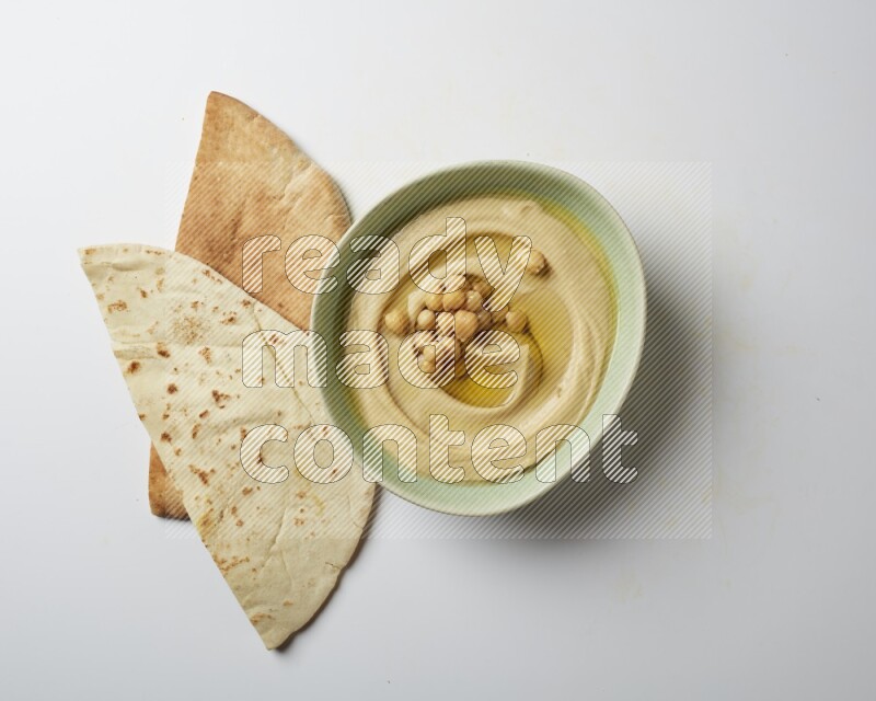 Hummus in a green plate garnished with roasted chickpeas  on a white background