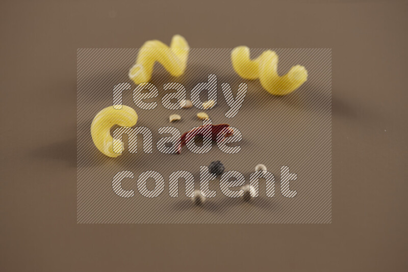 معكرونة مع مكونات متنوعة من الطماطم والثوم والبصل والفلفل الأحمر والفلفل الأسود والفلفل الأبيض وأوراق الغار وإكليل الجبل والهيل على خلفية بيج