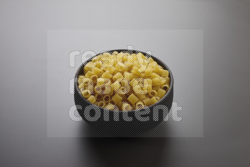 Big rings pasta in a pottery bowl on grey background