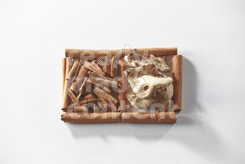2 squares of cinnamon sticks full of cinnamon and dried ginger on white flooring