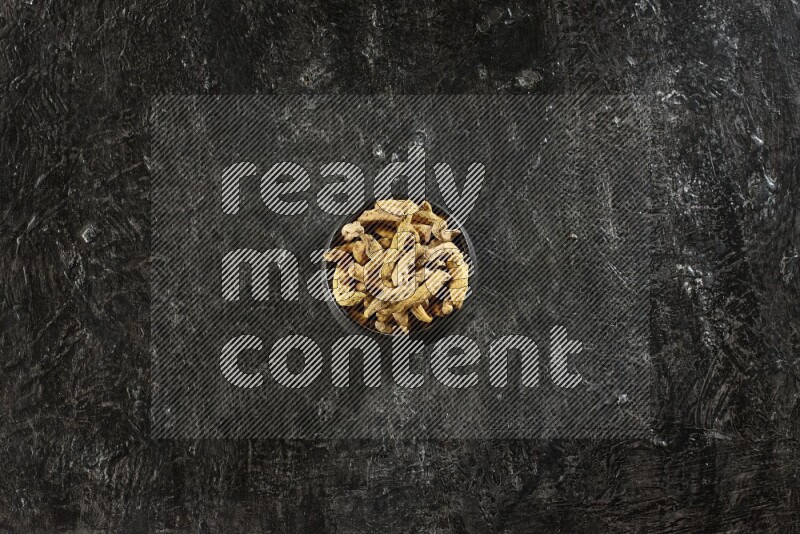 وعاء فخار أسود ممتلئ بأصابع كاملة من الكركم المجفف على خلفية سوداء