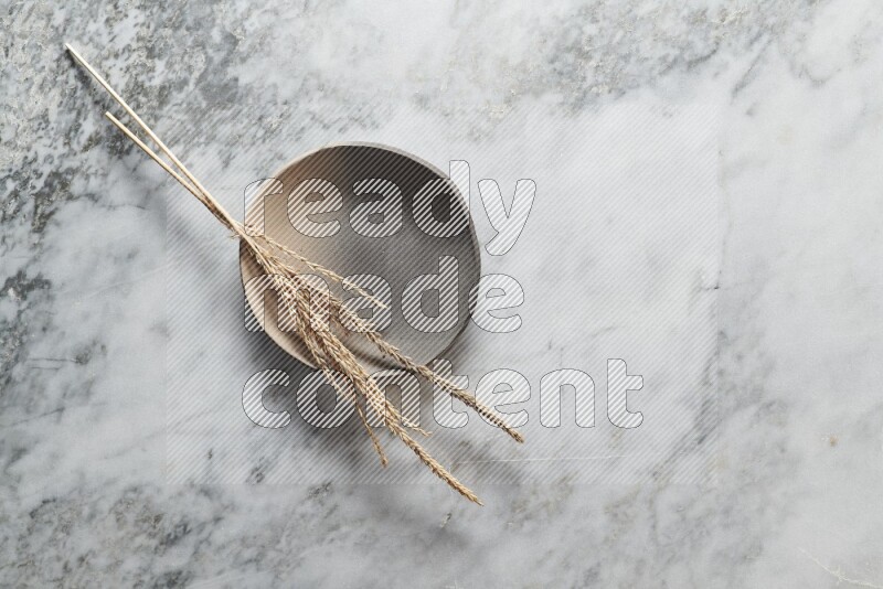 Wheat stalks on multicolored pottery plate on grey marble background