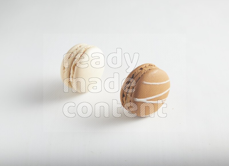 45º Shot of of two assorted Brown Irish Cream, and White Caramel fleur de sel macarons on white background