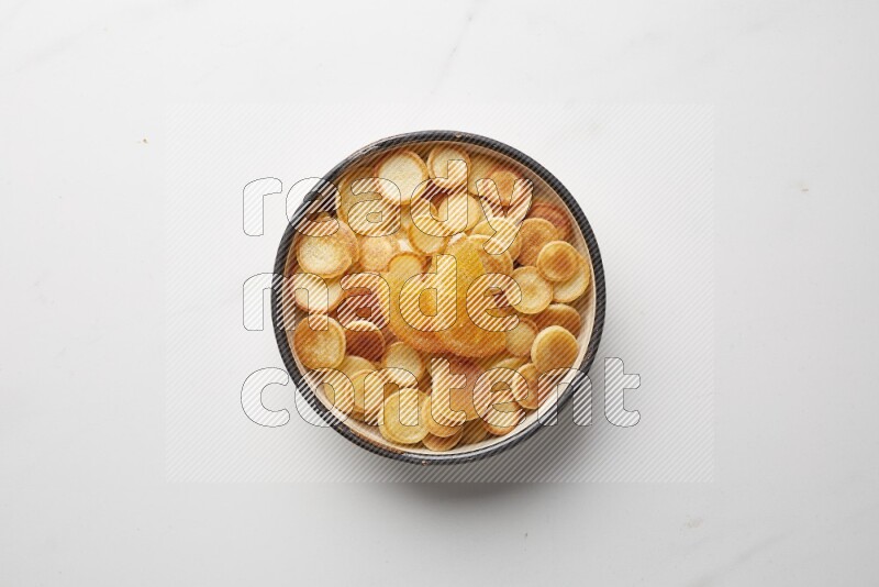 Top-view shot of orange candy cereal pancakes in a round bowl on white background