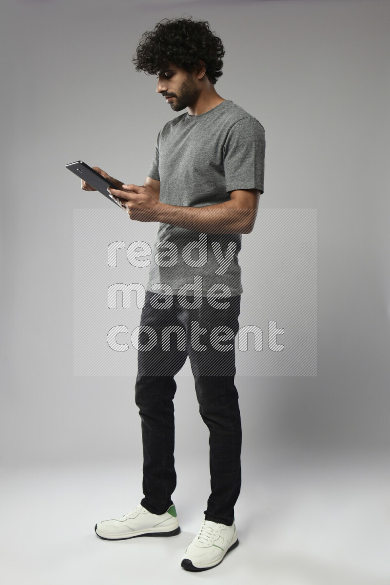 A man wearing casual standing and browsing on a tablet on white background