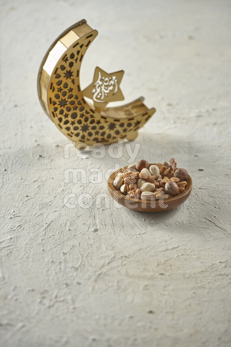 A wooden golden crescent lantern with different drinks, dates, nuts, prayer beads and quran on white background