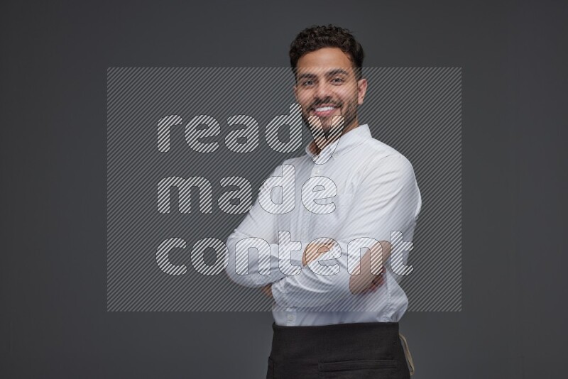 A man wearing smart casual and apron standing and making multi poses eye level on a gray background